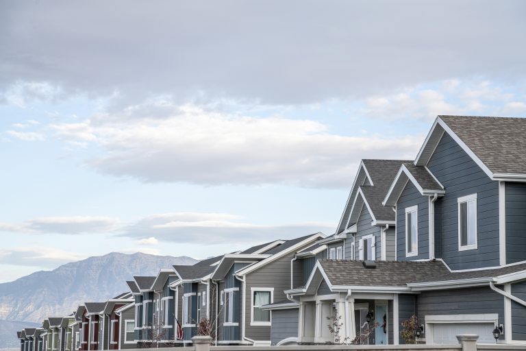 A line of gray residential modern buildings on background of mountain rocks