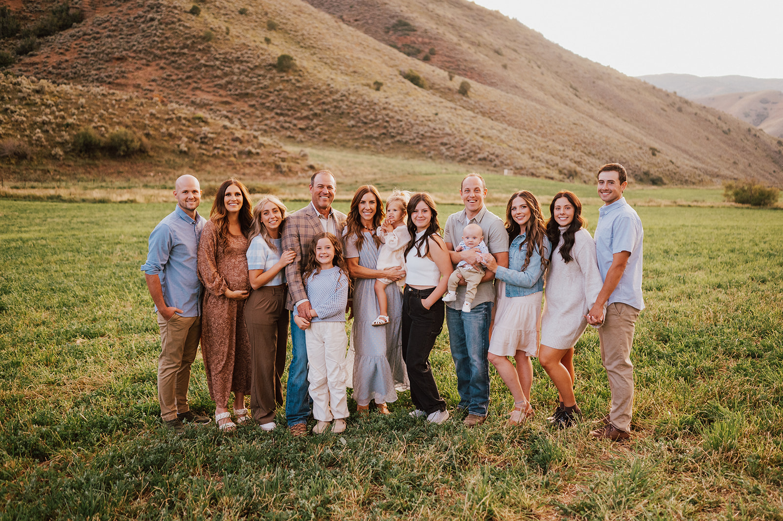 Speaker Mike Schultz with his wife, six children, and two grandchildren standing in a field for a family portrait