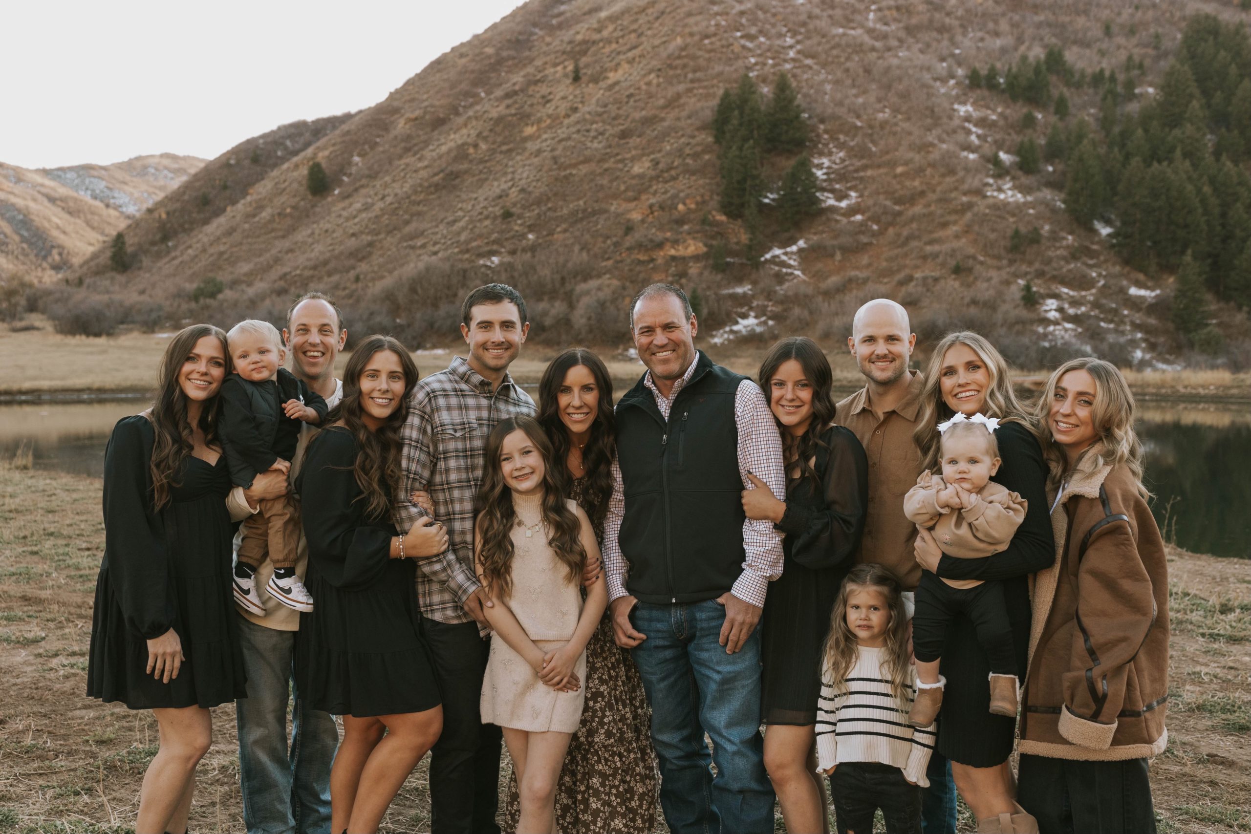 Speaker Mike Schultz with his wife, six children, and three grandchildren standing in a field for a family portrait